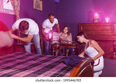 Group of young adults trying to find solution of quest in escape room with antique furnitures