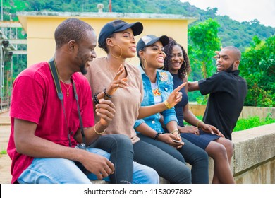 Group Of Young African Friends Hanging Out Together Outdoors Sitting And Laughing 