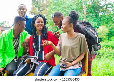 group of young african friends hanging out together outdoors on a bench and laughing as they discuss 