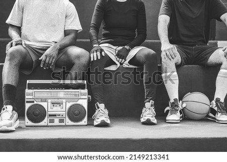 Group of young african people listening music outdoor after basketball match - Focus on boombox stereo - Black and white editing