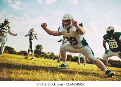 Group of young American football players doing drills while practicing outside together on a grassy field in the afternoon - Powered by Shutterstock