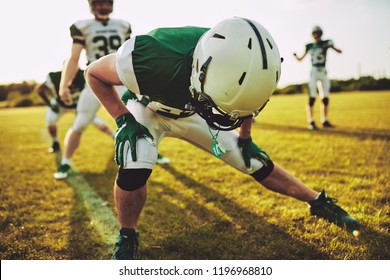 Group of young American football players stretching and warming up together during a practice outside on a sports field - Powered by Shutterstock