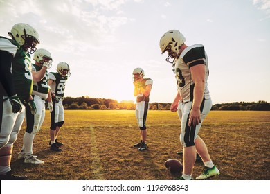 Group Of Young American Football Players Lining Up For A Practice Session On A Sportsfield Field In The Afternoon