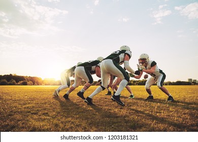 Group Of Young American Football Players Lining Up In Formation During A Practice Session On A Sports Field On A Sunny Afternoon