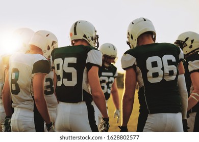 Group of young American football players standing in a huddle together before a late afternoon game - Powered by Shutterstock