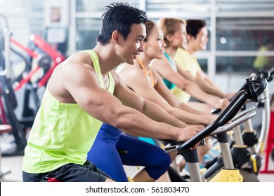 Group Of Young Asian Athletes Side By Side During Spinning Class Workout