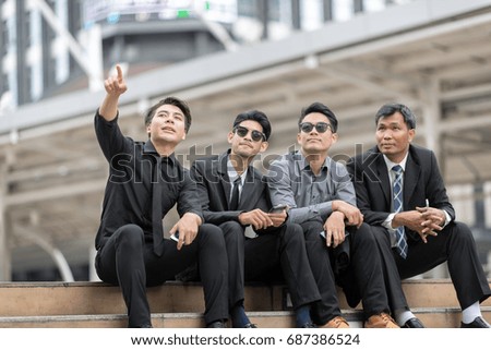 Group of Young asian businessman and businesswoman sitting outdoors and texting with their smartphones - Concepts about technology and global communication in the modern city,