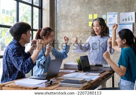 Group of young Asian businessmen raising their hands congratulating the success of the project. Passionate and excited about their work, success concept.