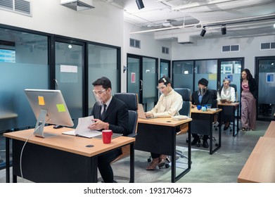 Group Of Young Asian Colleagues Working With Laptop At Desk In Modern Office. Female Manager Consulting With Employee. Business People Wearing Face Shiled Protective Against Coronavirus, Covid-19