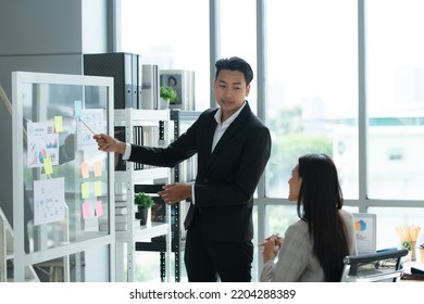 A Group Of Young Asian Entrepreneurs. Meeting To Review Stock Investment Data In A Meeting Room With Natural Light Windows.