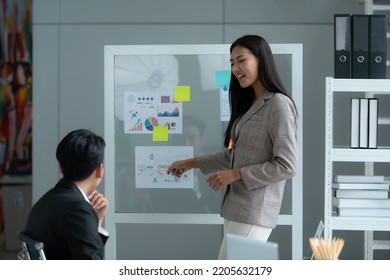 A Group Of Young Asian Entrepreneurs. Meeting To Review Stock Investment Data In A Meeting Room With Natural Light Windows.