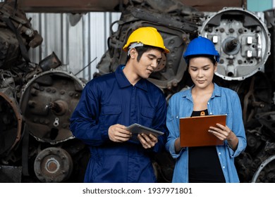 Group Of Young Asian Male And Female Employee Worker Using Clipboard Checking Old Automotive Spare Parts, Engine, Motor, Machine At The Garage Industry Factory Or Automotive Spare Parts Warehouse