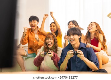 Group of Young Asian man and woman playing video games console together in living room at home. Happy generation z people friends enjoy and fun indoor lifestyle meeting party on holiday vacation. - Powered by Shutterstock