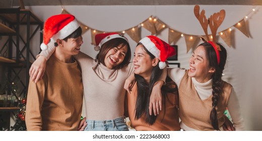 Group of young Asian man and women as friends having fun at a New Year's celebration, hugging singing laughing at a midnight countdown Party at home with Christmas tree decoration for holiday season. - Powered by Shutterstock