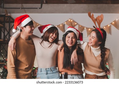 Group of young Asian man and women as friends having fun at a New Year's celebration, hugging singing laughing at a midnight countdown Party at home with Christmas tree decoration for holiday season. - Powered by Shutterstock