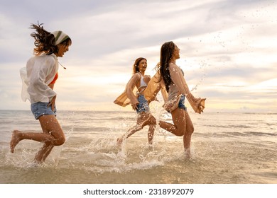 Group of Young Asian woman friends walking and playing together in the sea at tropical island beach at summer sunset. Attractive girl enjoy and fun outdoor lifestyle travel nature on holiday vacation. - Shutterstock ID 2318992079