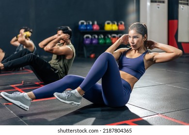 Group of young athlete male and female exercising together in fitness. Attractive handsome sportsman and sportswomen doing sit-up cardio workout to maintain strong muscle for health care in gym club.