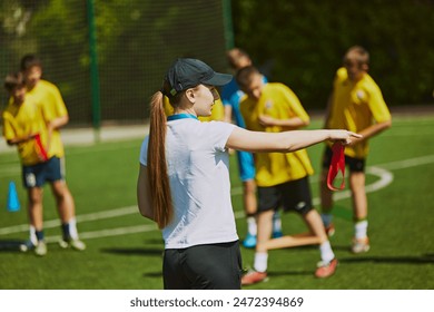 Group of young athletes, children training football outdoors with female coach on warm sunny day. Hobby and teamwork. Concept of sport, school, childhood, achievements, active lifestyle - Powered by Shutterstock