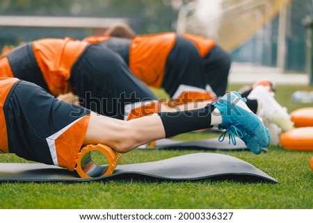 Group of Young Athletes on Stretching Outdoor Session with Foam Rollers and Mats. Soccer Football Players in a Team on Fitness Workout to Relieve Muscle Tightness, Soreness, and Inflammation