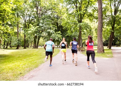 Group Of Young Athletes Running In Green Sunny Park.