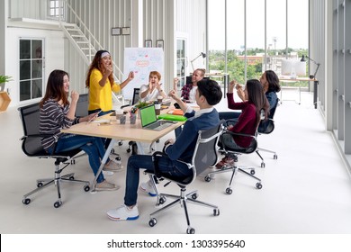 Group of young attractive asian creative design team meeting at office celebrating success or winner. Asian employee engaged together with effective and productive meeting and happy workplace concept.