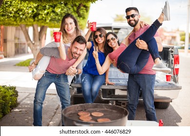 Group Of Young Attractive Friends Tailgating, Drinking Beer And Having Some Fun Together Next To A Grill