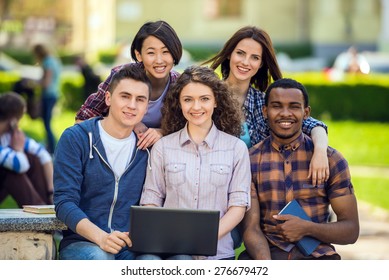 Group of young attractive smiling students dressed casual sitting on the staircase outdoors on campus at the university.
