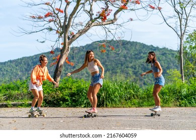 Group of Young beautiful Asian woman skateboarding together at skate park on summer vacation. Happy active female friends enjoy outdoor activity lifestyle and extreme sport surf skate at public park.