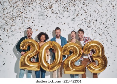 Group of young beautiful people in casual clothing carrying gold colored numbers and smiling - Shutterstock ID 2214422351