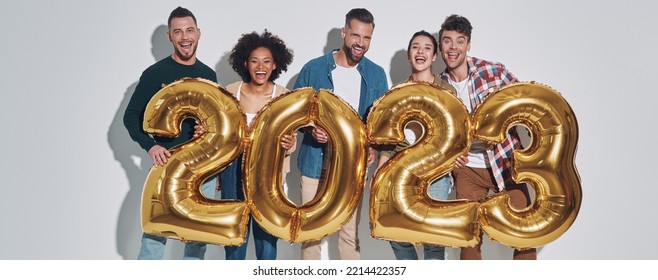 Group of young beautiful people in casual clothing carrying gold colored numbers and smiling - Shutterstock ID 2214422357