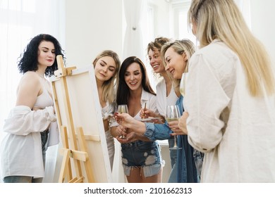 Group Of Young Beautiful Women Paint On Canvas And Drinking White Wine During Party At Home