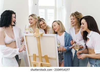 Group Of Young Beautiful Women Paint On Canvas And Drinking White Wine During Party At Home