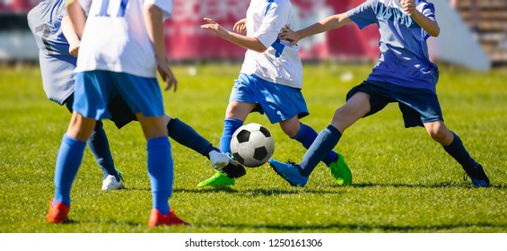 Group of Young Boys in Soccer Sportswear Running and Kicking Ball on the Soccer Grass Field. Low Angle Image of Youth Football Competition with Blurred Stadium Background