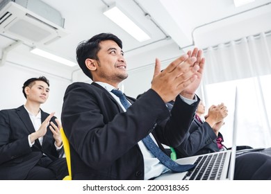 A Group Of Young Business Men Sat Listening Intently At The Presentation And Clapped In Unison. Make The Atmosphere In The Meeting Room Fun.