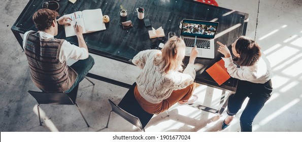 Group Of Young Business People In Bright Office Working Together And Sitting Near Big Black Desk. Video Call Conference. Wide Screen