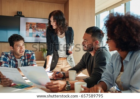 Group of young business people discussing new color scheme for project. Team brainstorming in meeting room with color palettes.