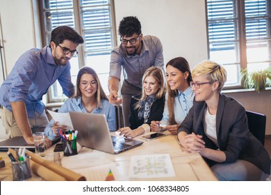  Group of young business people in smart casual wear working together in creative office using laptop. - Shutterstock ID 1068334805