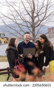 Group of young business people are smiling and looking at the lap top while standing outside - Shutterstock ID 2205650655