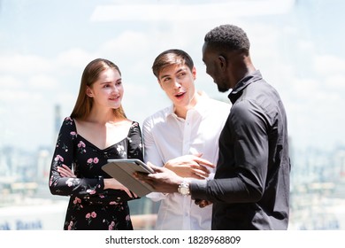 Group Of Young Business People Working And Communicating With Digital Tablet. Diverse Creative Business Team Standing And Talking Together Over Cityscape Blur Background. Business, People, Technology 