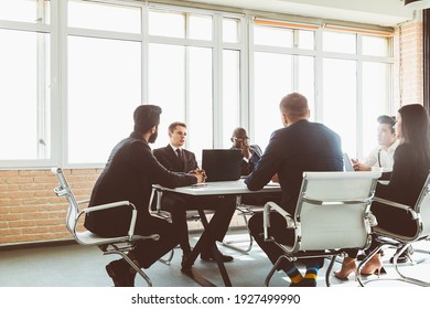 Group Of Young Business People Working And Communicating While Sitting At The Office Desk Together With Colleagues Sitting. Business Meeting