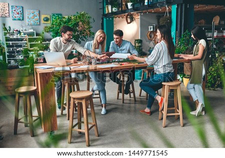 Group of young business people are working together in modern office. Creative people with laptop, tablet, smart phone, notebook. Successful hipster team in coworking. Freelancers.