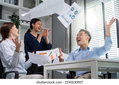 Group of young businessman and businesswoman people working in office. Attractive employee feel happy throwing paper in the air after finish work sale projct. Corporate of modern colleagues concept.