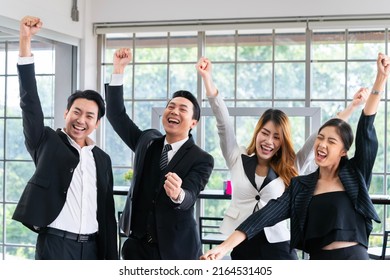 A group of young businessmen in suits, Asians, are determined and excited about their work. and encourage the team members by raising their hands happily - Powered by Shutterstock