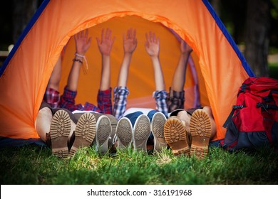 Group of young campers lying down in a tent with their hands up