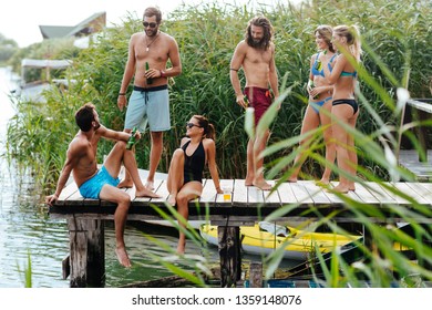 Group of young Caucasian people drinking beer on a wooden pier. - Powered by Shutterstock