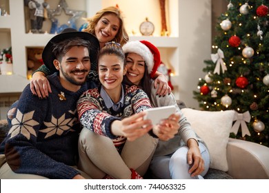 Group of young cheerful people taking Christmas selfie at home