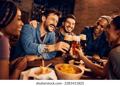 Group of young cheerful people toasting while drinking beer  in a pub.  - Powered by Shutterstock