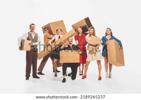 Group of young cheerful, stylish people holding big cardboard boxes isolated over white studio background. Black Friday, sales, shopping. Concept of retro fashion, style, youth culture, emotions, ad