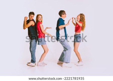 Group of young, cheerful, stylish people dancing isolated on grey background. Friends meeting at the party. Bright makeup, jeans clothes. Concept of youth, retro style, 90s era, fashion, lifestyle, ad