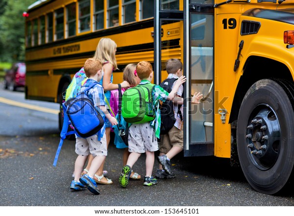 A group\
of young children getting on the\
schoolbus